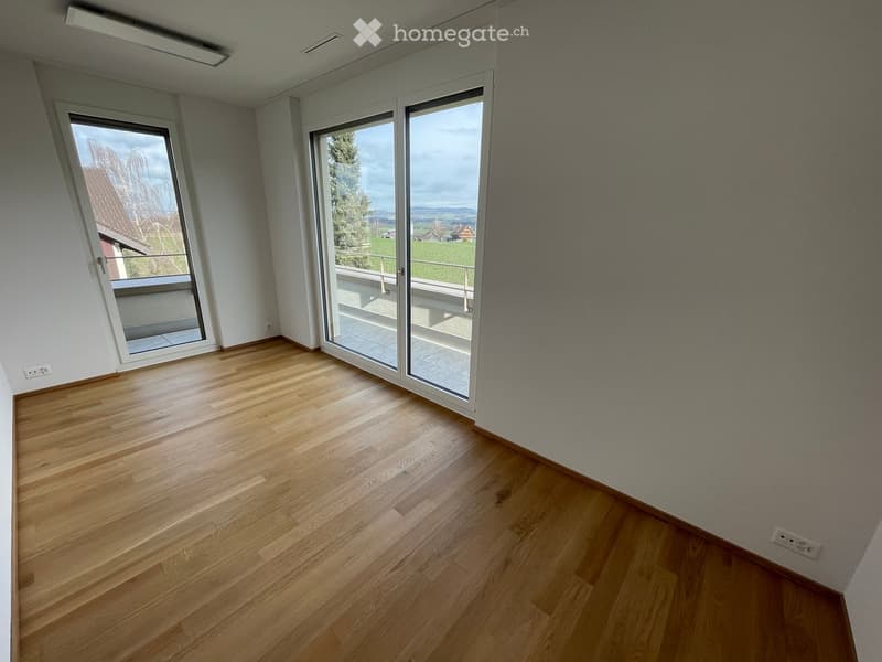 Empty room with wooden flooring, large windows, and a view of a green landscape.