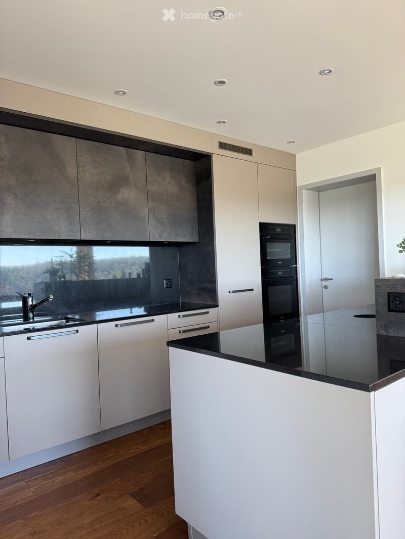 Modern kitchen with white cabinets, black countertops, and stainless steel appliances, including a sink, faucet, and oven.