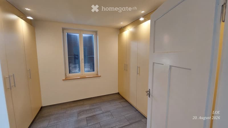 Empty room with tiled floor, white walls, built-in wardrobes, and a window with blinds.