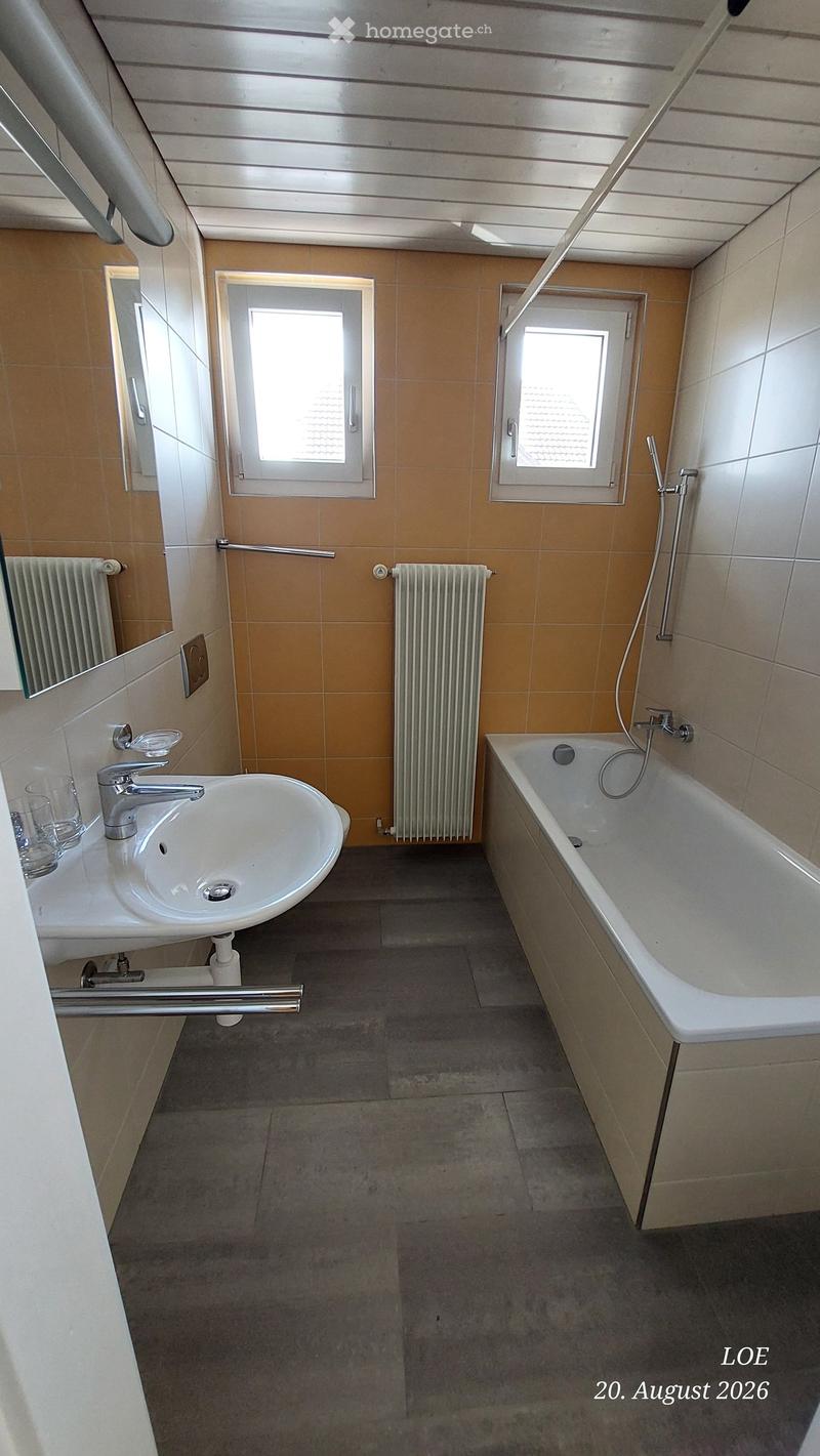 Bathroom with a sink, bathtub, radiator, and mirror. The room has tiled walls and a tiled floor.