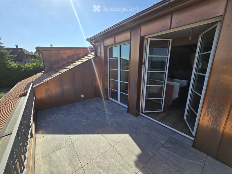 Balcony with tiled floor, metal railing, and large glass doors leading to the interior.