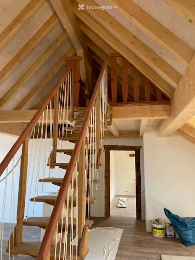 wooden staircase, wooden beams, wooden floor, white walls, open door