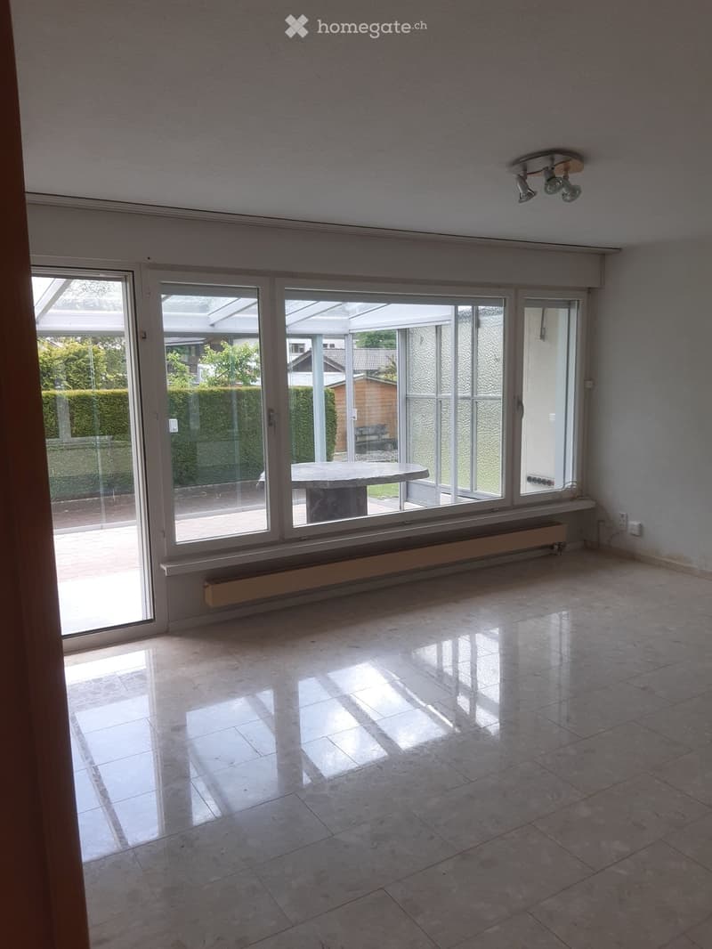 Empty room with large glass sliding doors leading to an outdoor area, tiled floor, and visible radiator under the windows.