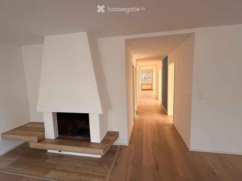 Modern hallway with wooden flooring, white walls, and a built-in fireplace with a stone surround and wooden seating area.