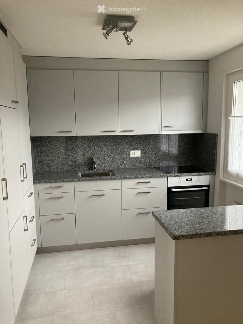 Modern kitchen with white cabinets, granite countertops, and stainless steel appliances.