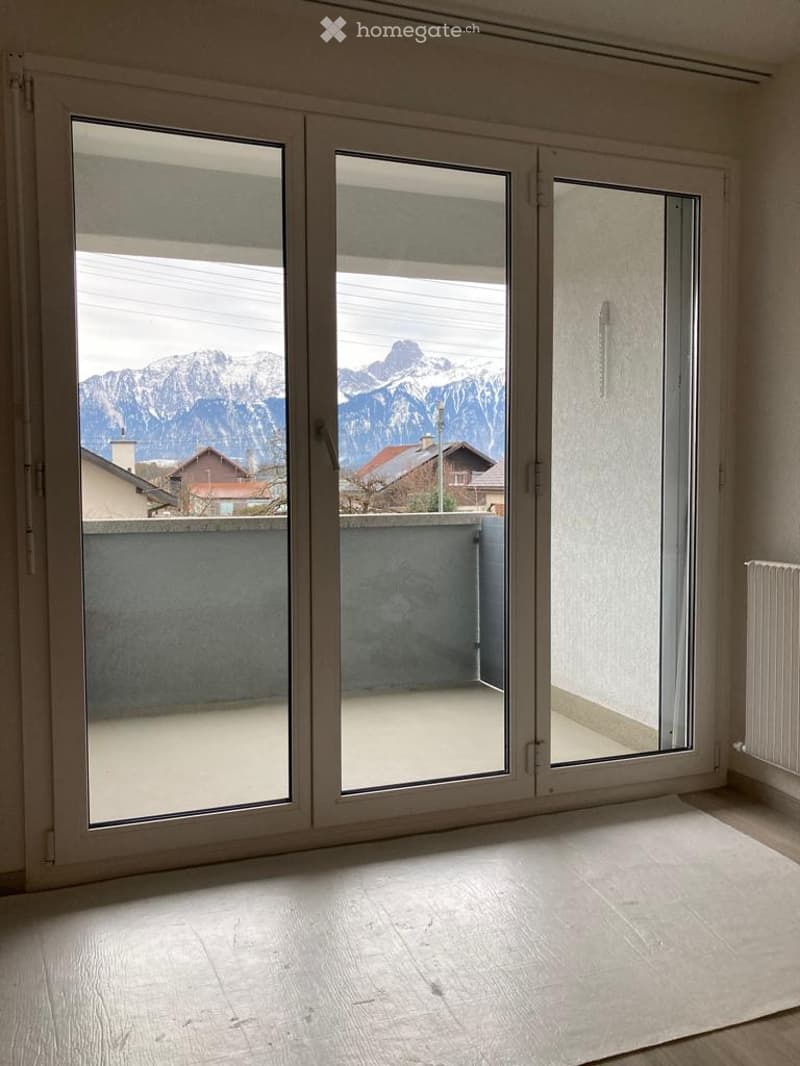 Empty room with large sliding glass doors opening to a balcony, offering a scenic mountain view. The floor is light-colored wood.