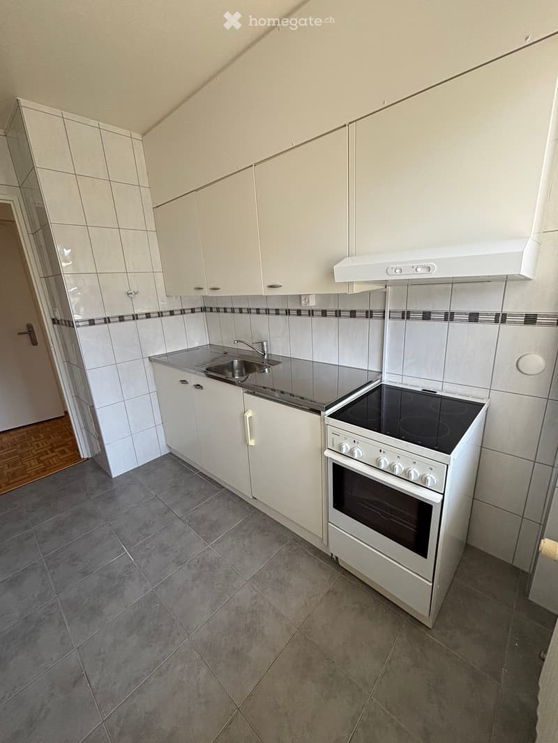 Modern kitchen with white cabinets, stainless steel sink, electric oven, and tiled backsplash.