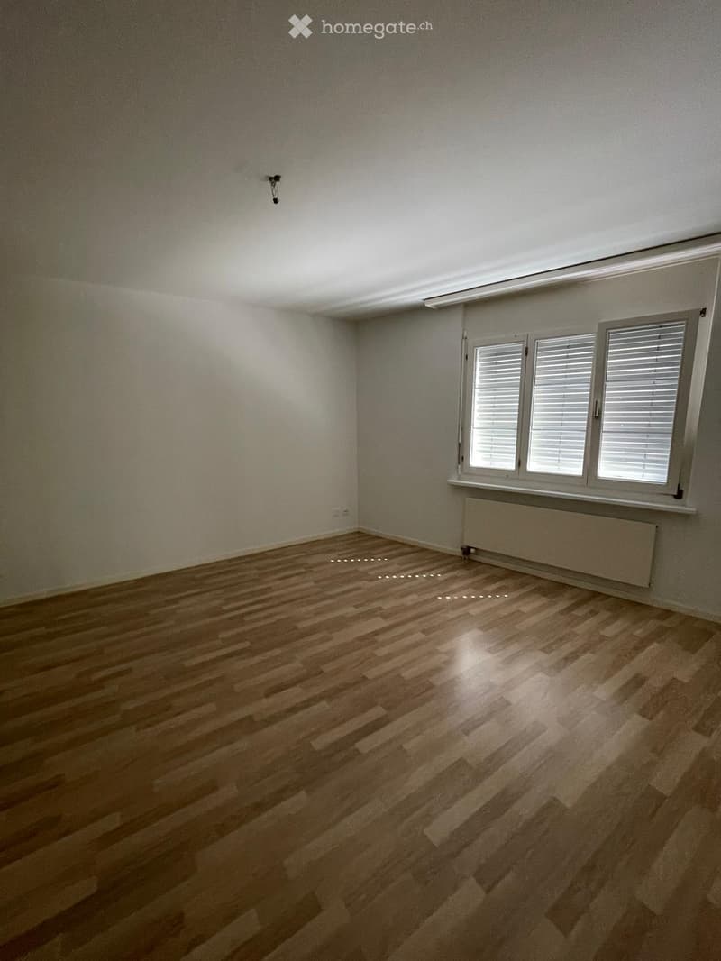 Empty room with wooden flooring, white walls, and large windows with blinds. No furniture or equipment present.