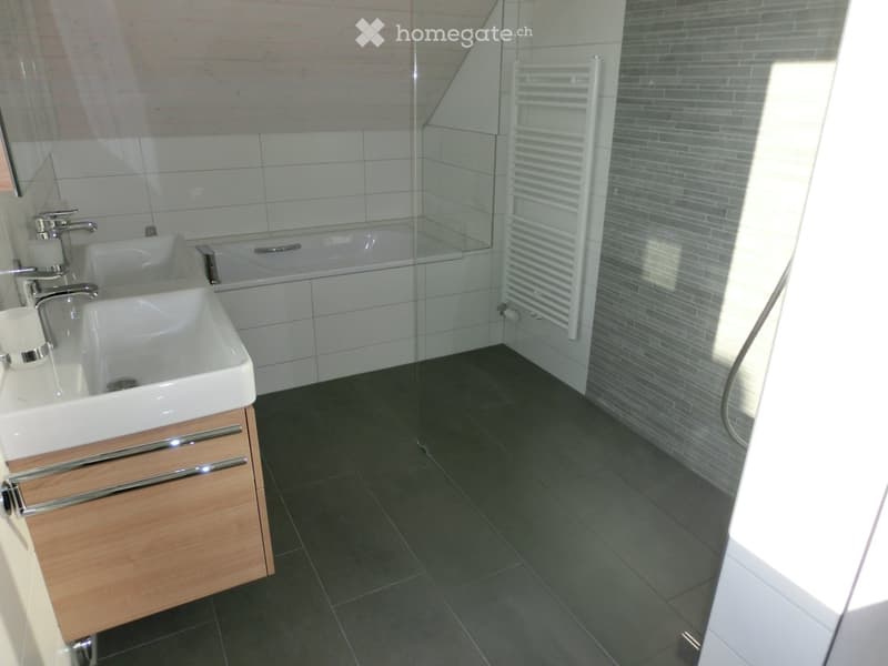 Modern bathroom with a double sink, bathtub, radiator, and wooden cabinet.