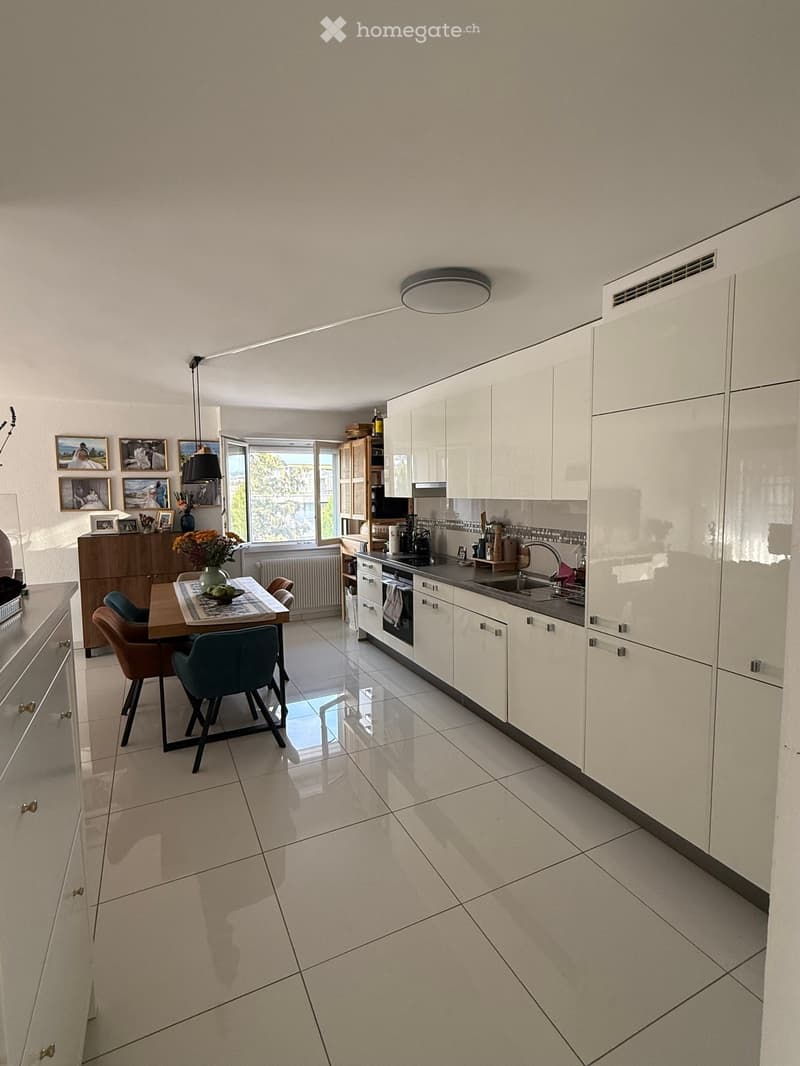 Modern kitchen with white cabinets, stainless steel appliances, a central island, and a dining area with a table and chairs.