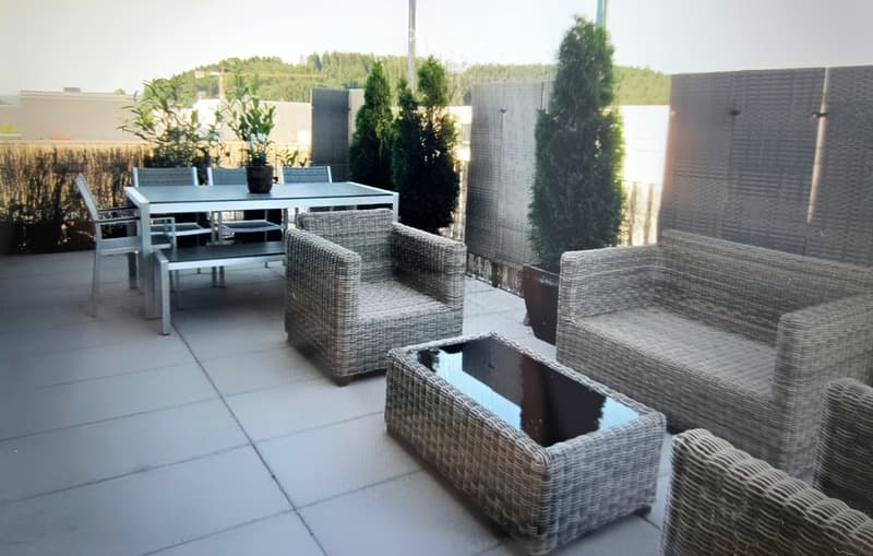 A modern outdoor patio with wicker furniture, including a sofa, coffee table, and dining area with a table and chairs.