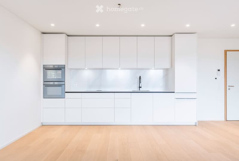 Modern kitchen with white cabinets, stainless steel oven, and a sleek sink with a modern faucet.