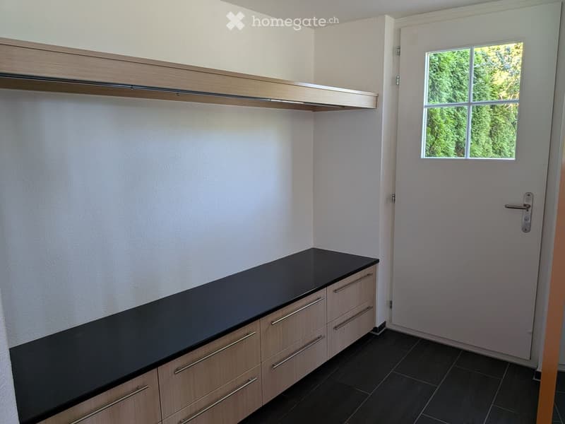 Modern kitchen with black countertop, light wood cabinets, and built-in shelving above.