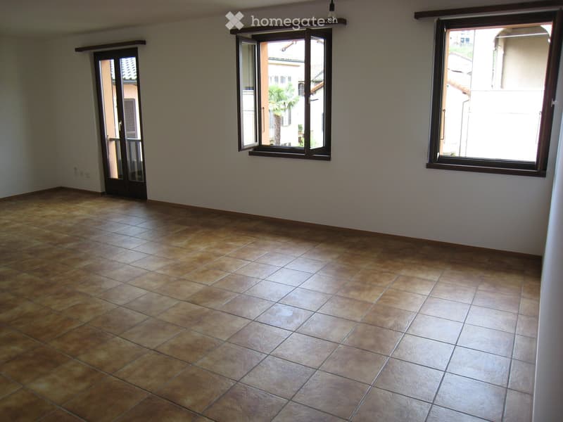 Empty room with tiled flooring, large windows, and a door leading outside.