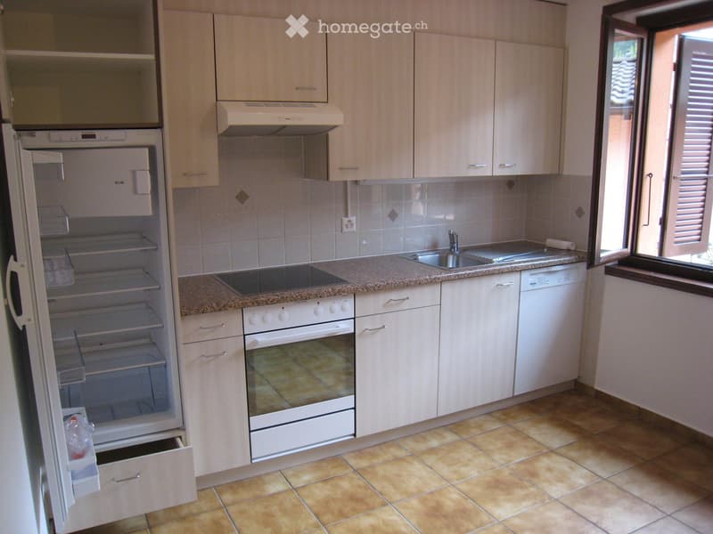 Modern kitchen with light wood cabinets, granite countertop, stainless steel sink, and built-in appliances including a refrigerator, oven, and dishwasher.