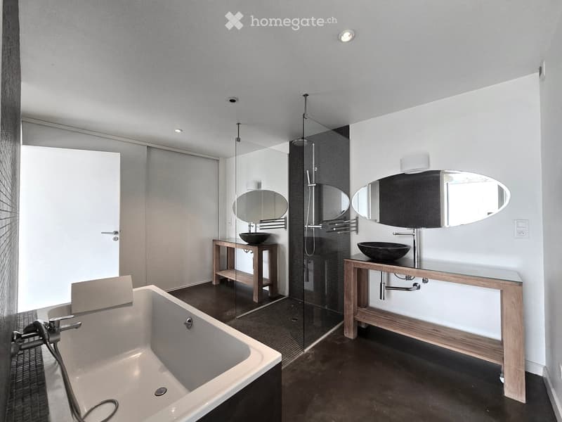 Bathroom. Modern bathroom with a freestanding bathtub, two sinks with wooden vanities, large oval mirrors, and a glass-enclosed shower area.