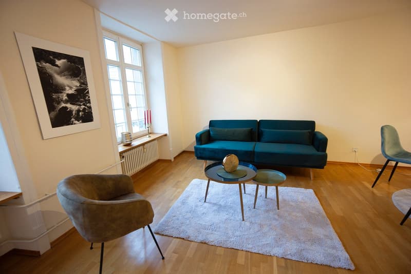 Modern living room with wooden flooring, a blue sofa, a coffee table, and a white shag rug.