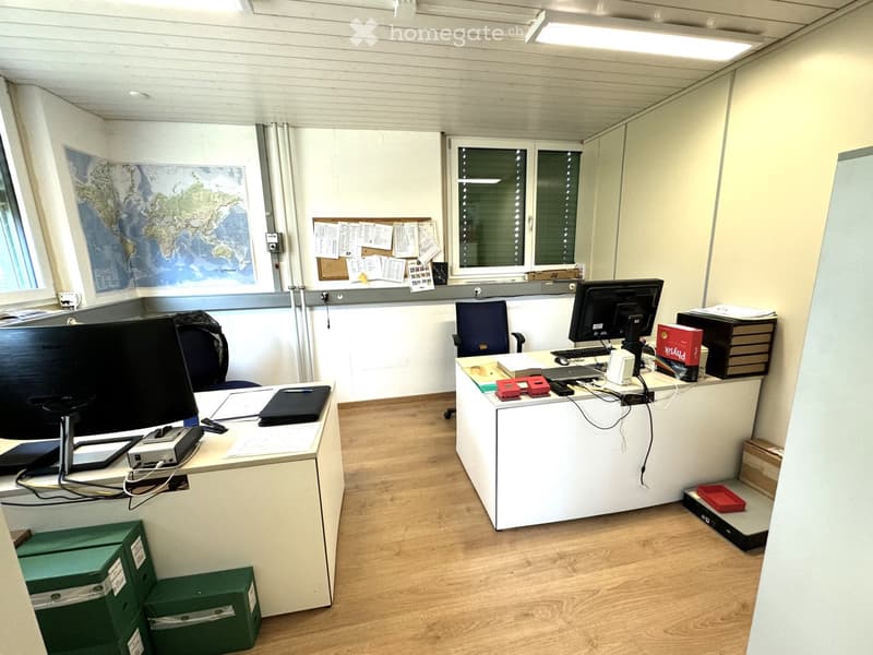 Two desks, two monitors, office chairs, bulletin board, map on the wall, storage boxes, wooden floor