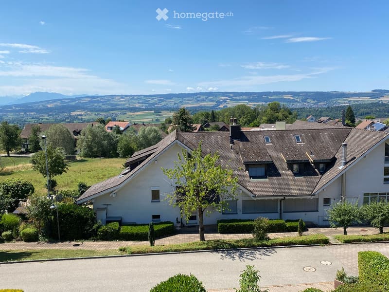 Single-family house with a tiled roof, multiple windows, and a well-maintained garden, situated in a scenic countryside with distant hills and fields.