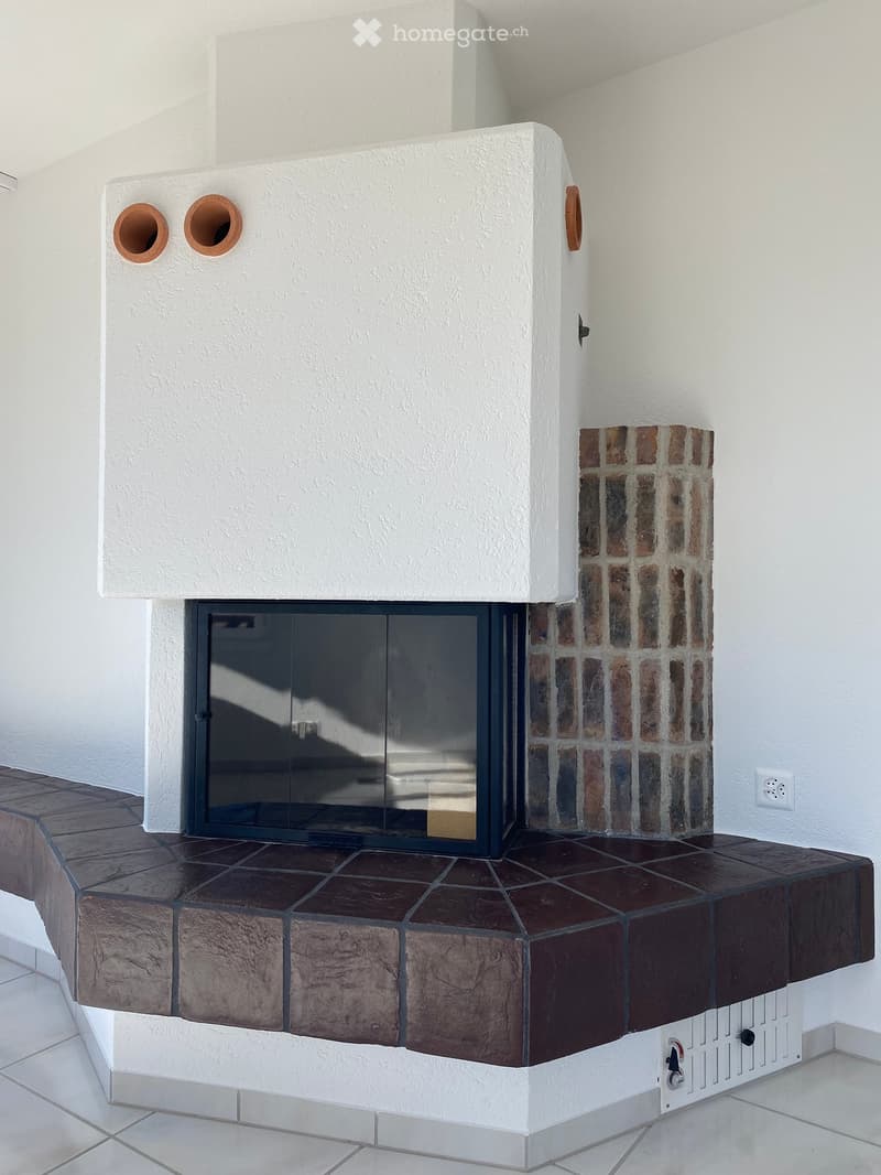 Modern fireplace with a glass front, white textured surround, and a brick accent wall.
