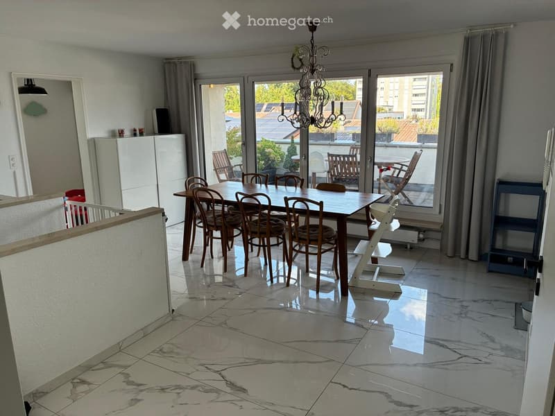 Dining room with marble flooring, large windows leading to a balcony, dining table with chairs, refrigerator, and a baby chair.