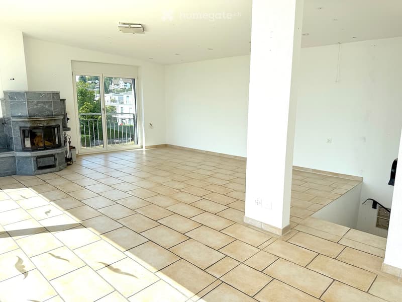 Empty room with tiled floor, white walls, fireplace, and large sliding glass doors leading to a balcony.