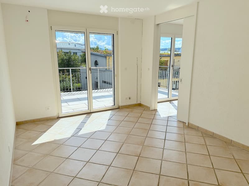 Empty room with tiled floor, white walls, and large sliding glass doors leading to a balcony with a view of the outdoors.