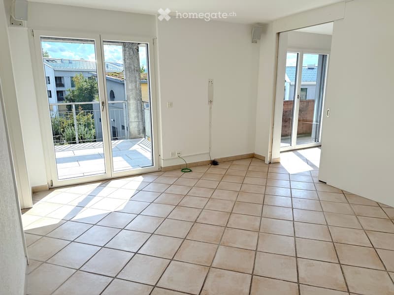 Empty room with tiled floor, white walls, and large sliding glass doors leading to a balcony.