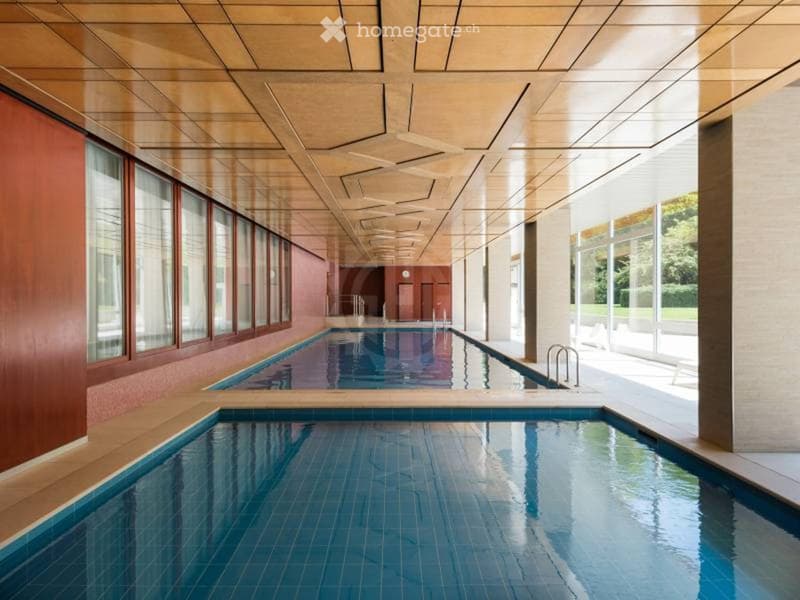 Indoor swimming pool area with two pools, large windows, and a modern ceiling design.