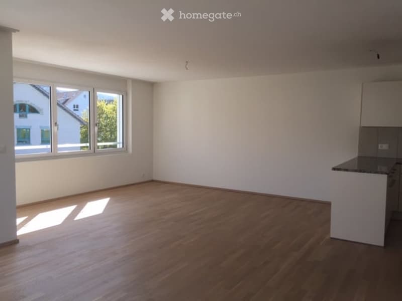 Empty room with wooden flooring, white walls, and large windows allowing natural light. No furniture or equipment present.