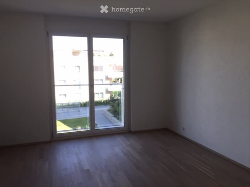 Empty room with wooden flooring and large sliding glass door leading to a balcony or outdoor area.