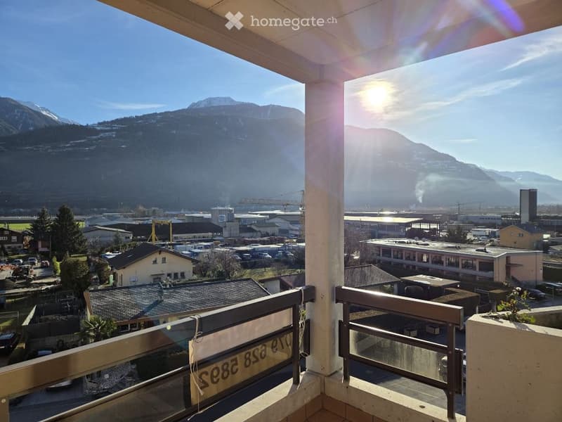 Balcony with a view of mountains, a town, and a sun shining