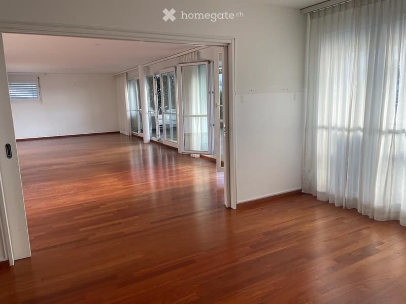 Empty room with wooden flooring, large glass sliding doors, and white walls.