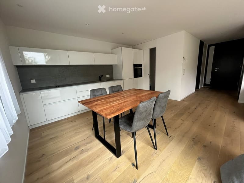 Modern kitchen with white cabinets, a wooden dining table, and four grey chairs.