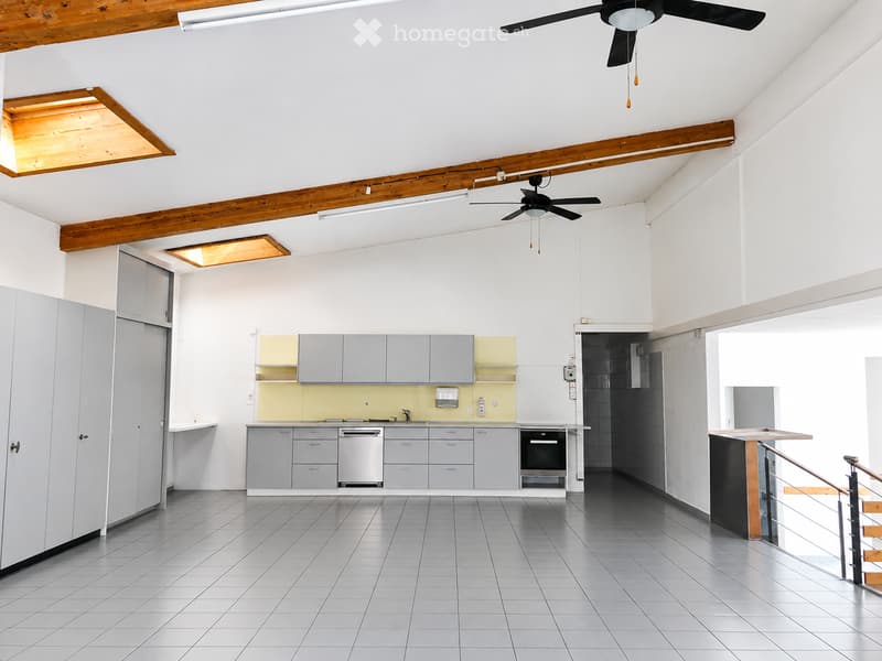 Modern kitchen with grey cabinets, stainless steel appliances, and a yellow backsplash. Features a central island with a staircase leading upwards.
