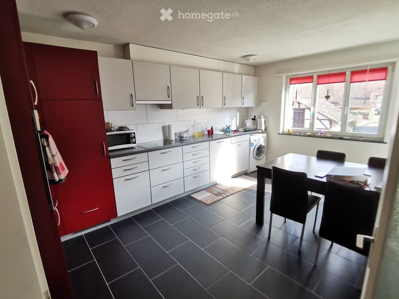 Kitchen. Modern kitchen with white and red cabinets, black tiled floor, and a dining area with a table and chairs.