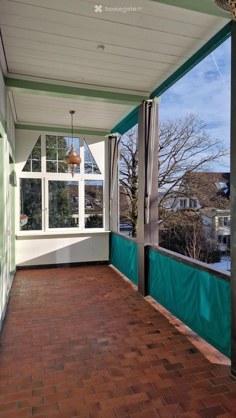 Balcony with brick floor, green railings, large windows, chandelier