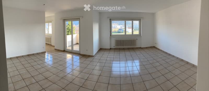 Empty room with tiled floor, white walls, large windows, and a sliding glass door leading to a balcony.