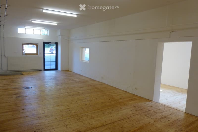 Empty room with wooden flooring, white walls, and large windows. No furniture or equipment present.