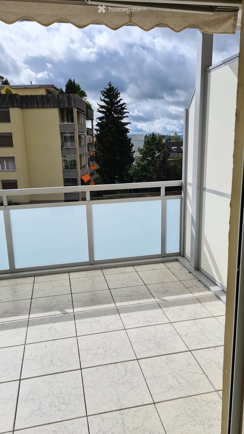 Modern balcony with glass wall, tiled floor, a view of another building