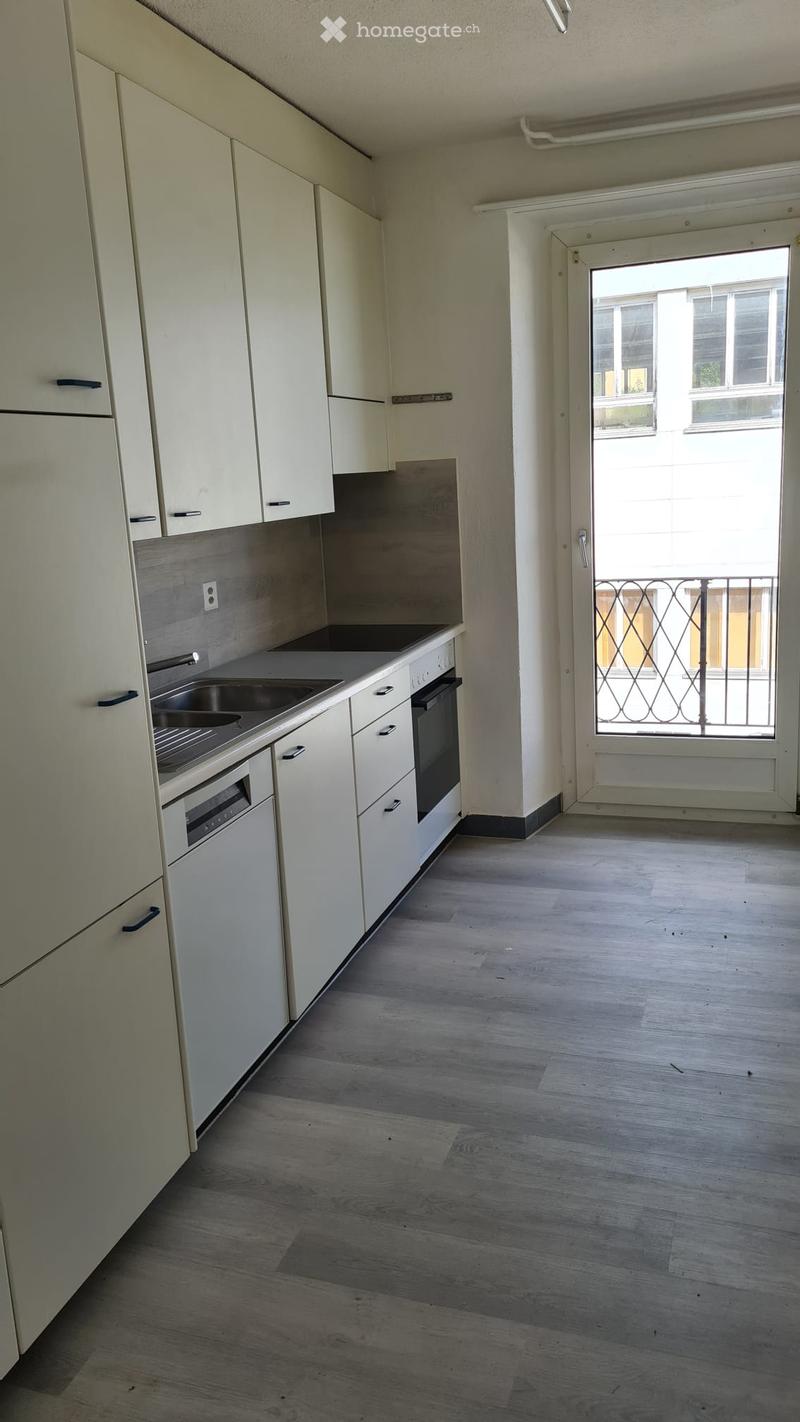 Modern kitchen with white cabinets, black stove and dishwasher, sink and faucet, balcony door