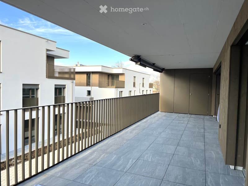 Modern balcony with tiled floor, metal railing, and view of neighboring buildings.