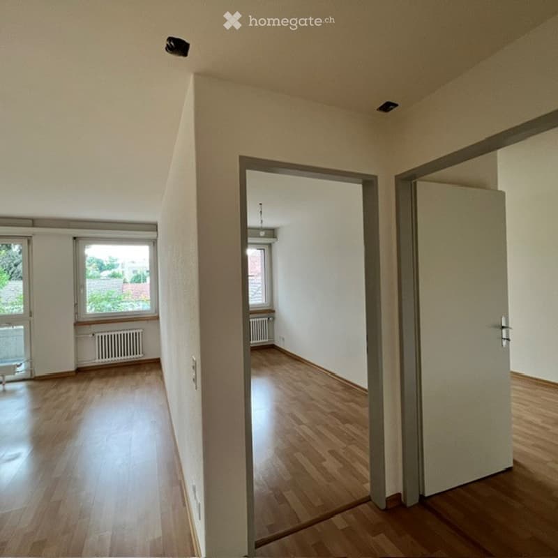 Empty room with wooden flooring, white walls, and large windows. No furniture or equipment present.