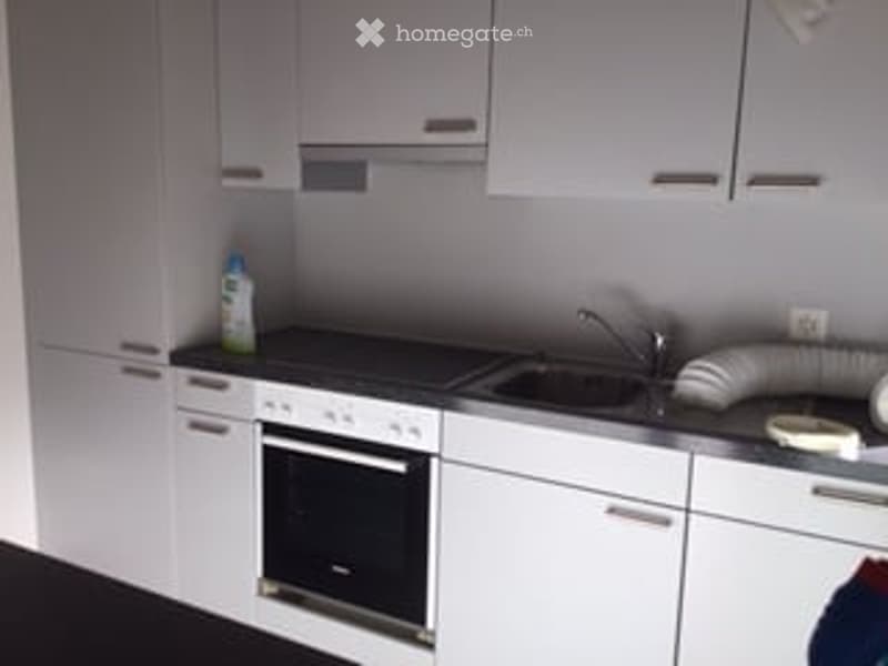 Modern kitchen with white cabinets, a built-in oven, a sink with a faucet, and a countertop.