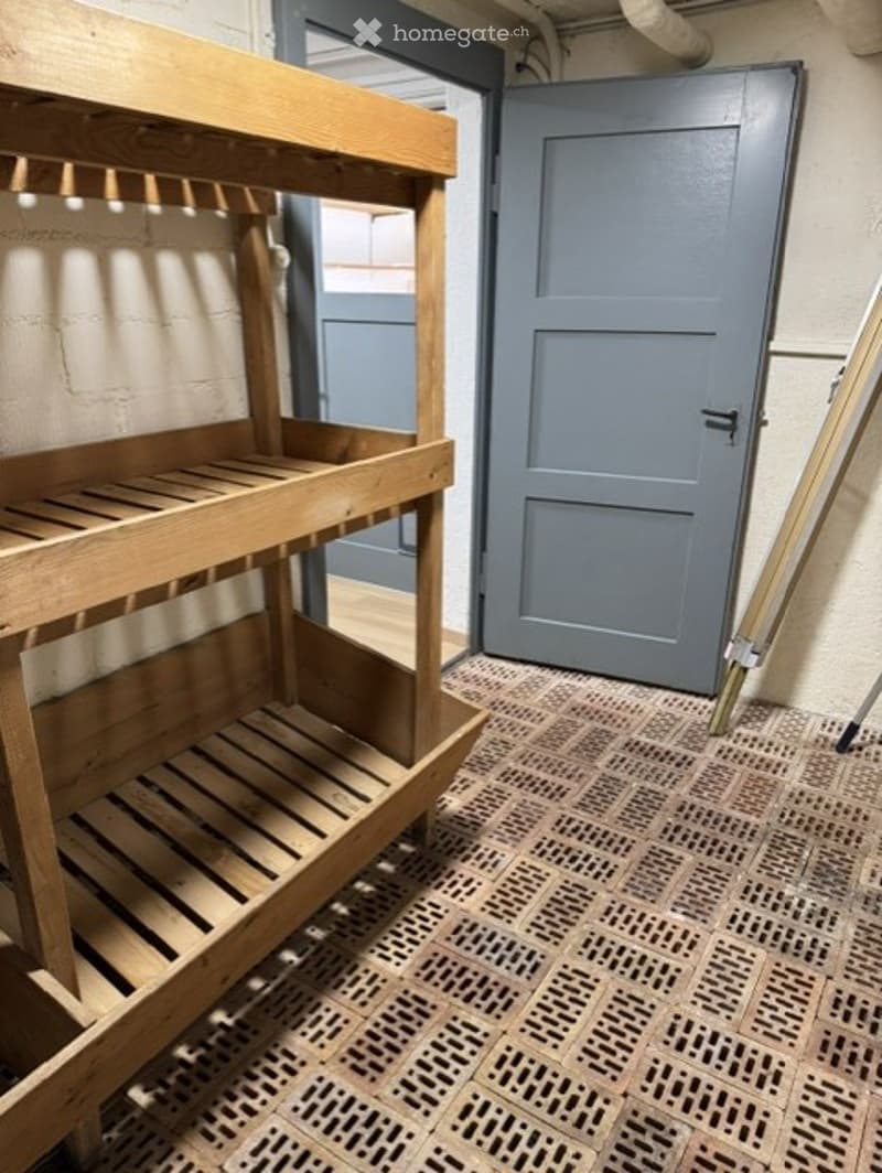 Empty room with wooden shelving unit, grey door, and patterned tile floor.