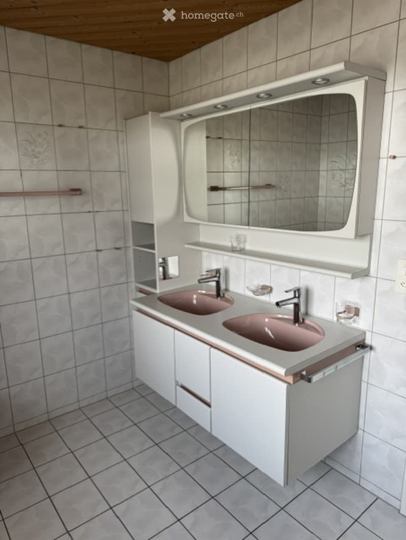 Modern bathroom with double sinks, white cabinets, and a large mirror with built-in lighting.