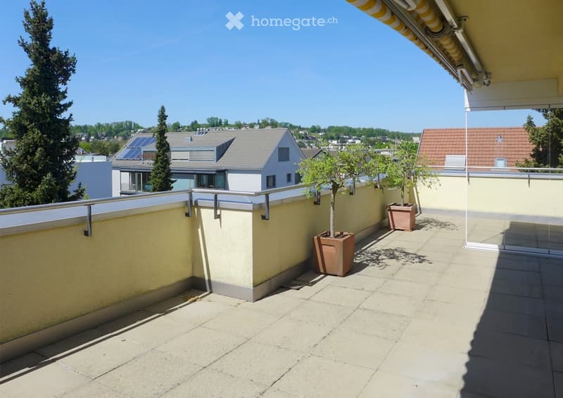 Balcony with tiled floor, metal railing, potted plants, and a view of the surrounding area.