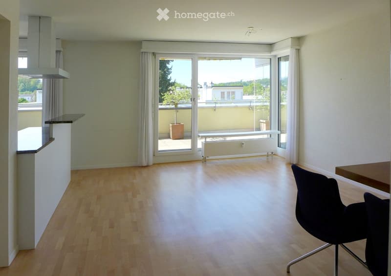 Empty room with wooden flooring, white walls, and large windows leading to a balcony. No furniture or equipment is present.