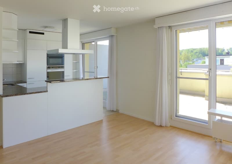 Modern kitchen with white cabinets, stainless steel oven, range hood, and granite countertop. Large windows and sliding doors lead to a balcony.