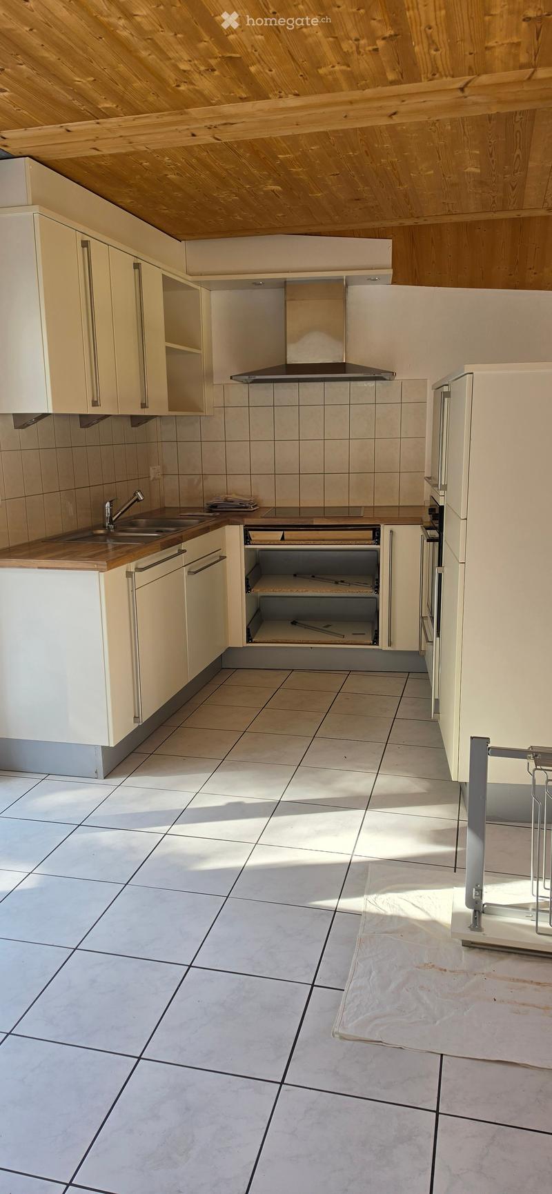 Modern kitchen with light-colored cabinets, a stainless steel range hood, a sink with a faucet, and tiled flooring.